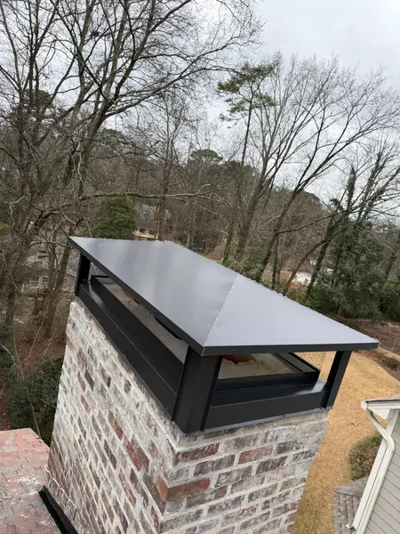 Custom metal chimney chase cover with a wide overhang installed over a brick chase