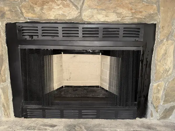 Same fireplace firebox after masonry restoration with clean light-colored firebrick