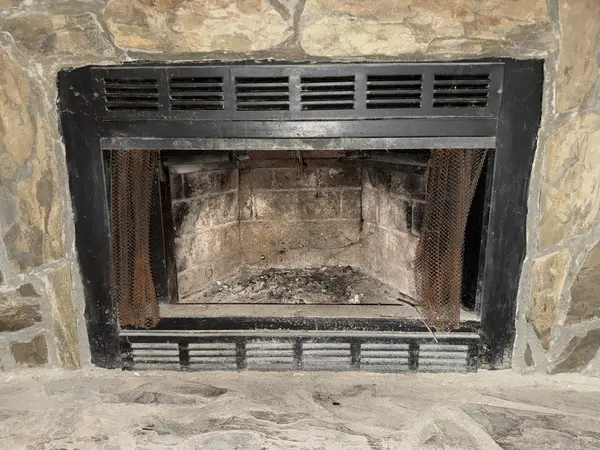 Fireplace firebox before masonry restoration with worn interior surfaces