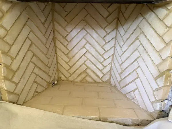 Completed herringbone firebrick pattern inside a fireplace firebox