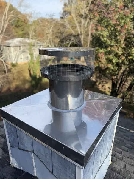 Metal chimney liner top plate and round rain cap installed above masonry