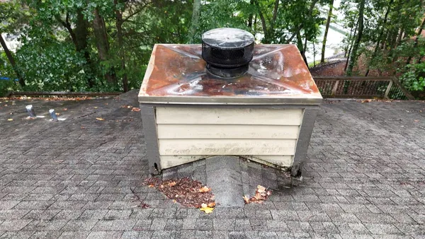 Marietta chimney chase before repair with a rusted metal cover and deteriorated lower trim