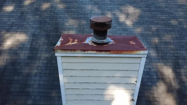 Marietta chimney chase before replacement, with a rusted cover and weathered siding and trim
