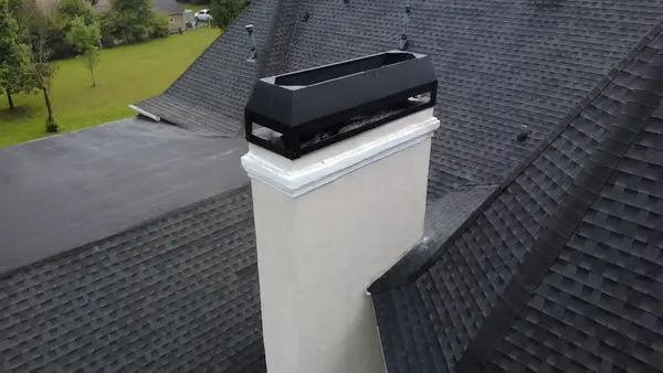 Wide black multi-flue chimney cap installed over a masonry chimney top