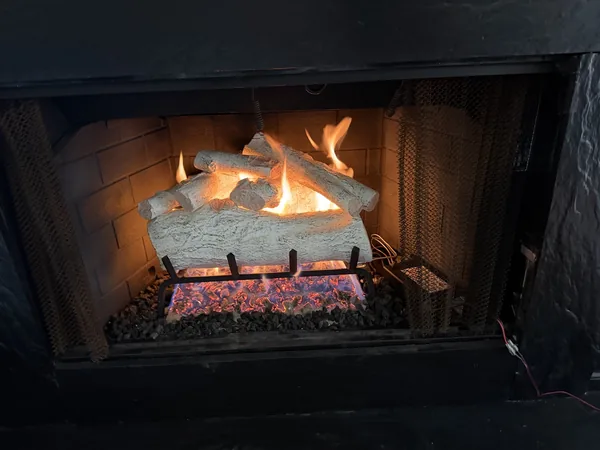 Same Roswell fireplace after gas-system installation, with gas logs and flames visible